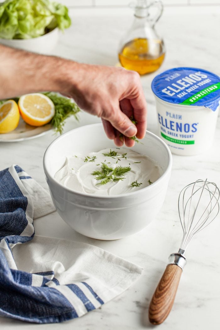 Hand garnishing a fresh bowl of Tzatziki made with Ellenos Greek yogurt