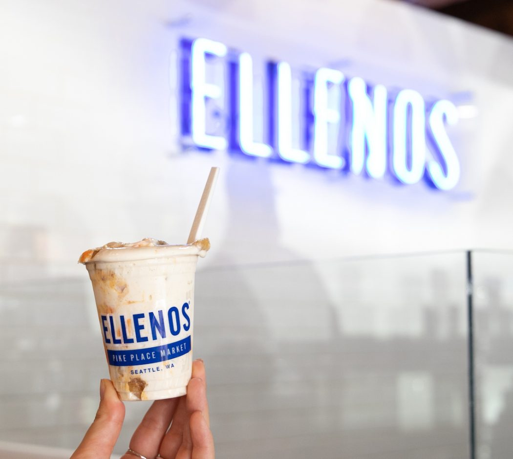 Walkaround cup of Ellenos Greek yogurt at Pike Place Market scoop shop, in front of Ellenos neon sign.