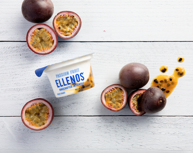 A cup of Passion Fruit Ellenos surrounded with sliced Passion Fruits